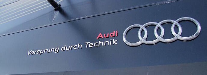 Audi's tagline, says Vorsprung durch technik, written on a black storefront