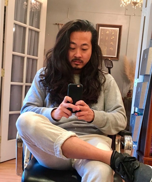 Tyler Lau pictured sat on a chair using his mobile phone in his social media work