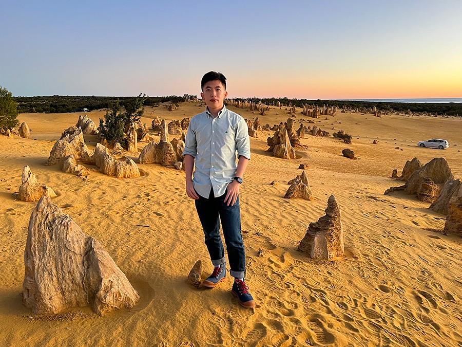 Huanyi standing on a sandy beach.