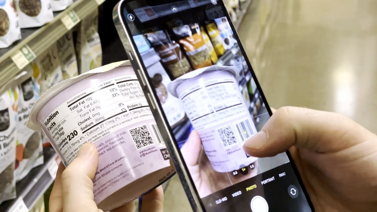 Close up of person using their phone to click on a QR code on a package in a grocery store.