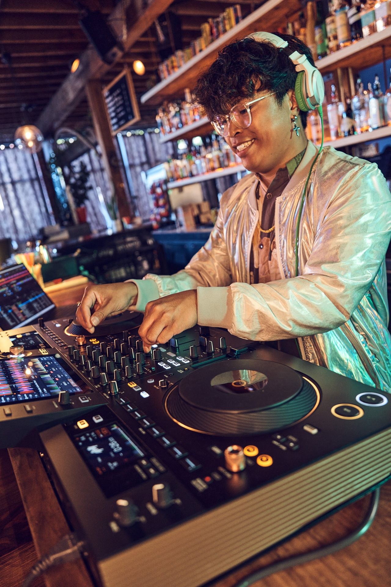 Person wearing headphones in a bar using the Pioneer DJ's OPUS-QUAD