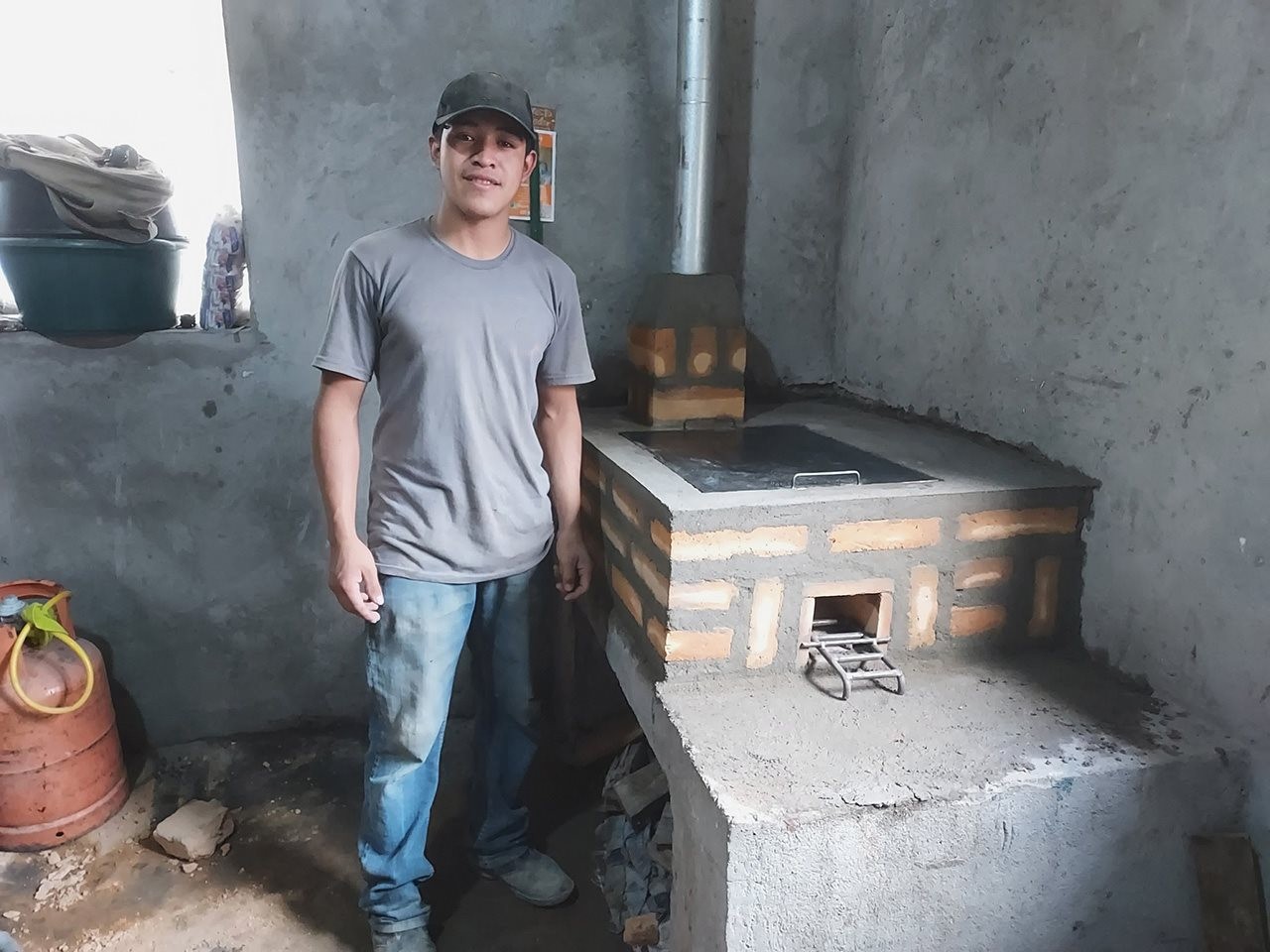 Young man standing next to a stove in a cabin