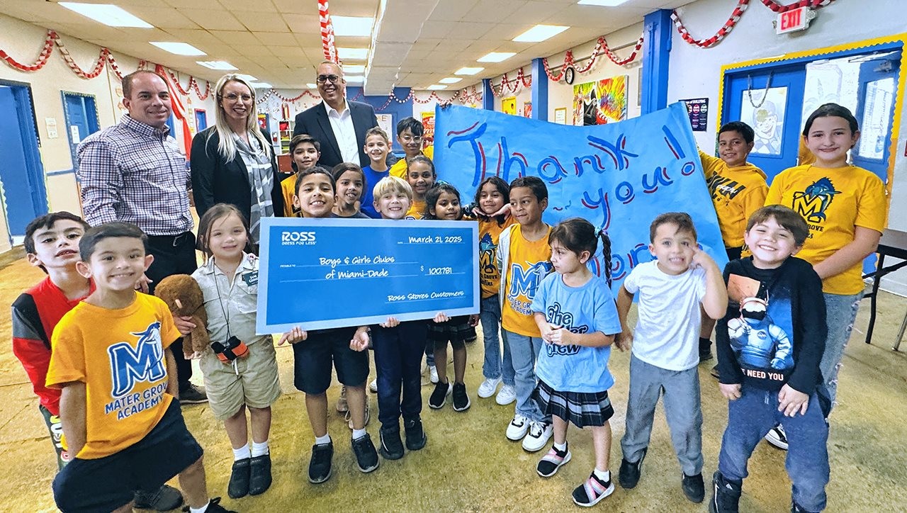 Small children in a classroom holding a giant check from ROSS and a sign that says